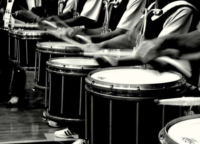 Image focused on drumsticks beating in a marching band drumline