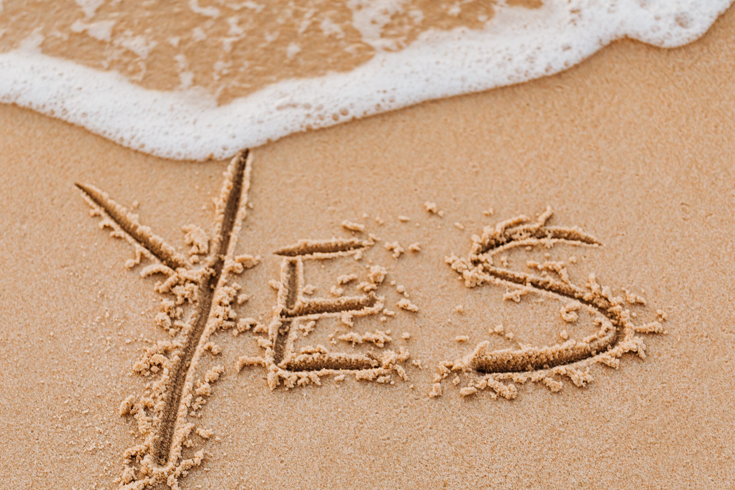The word YES carved in sand.
